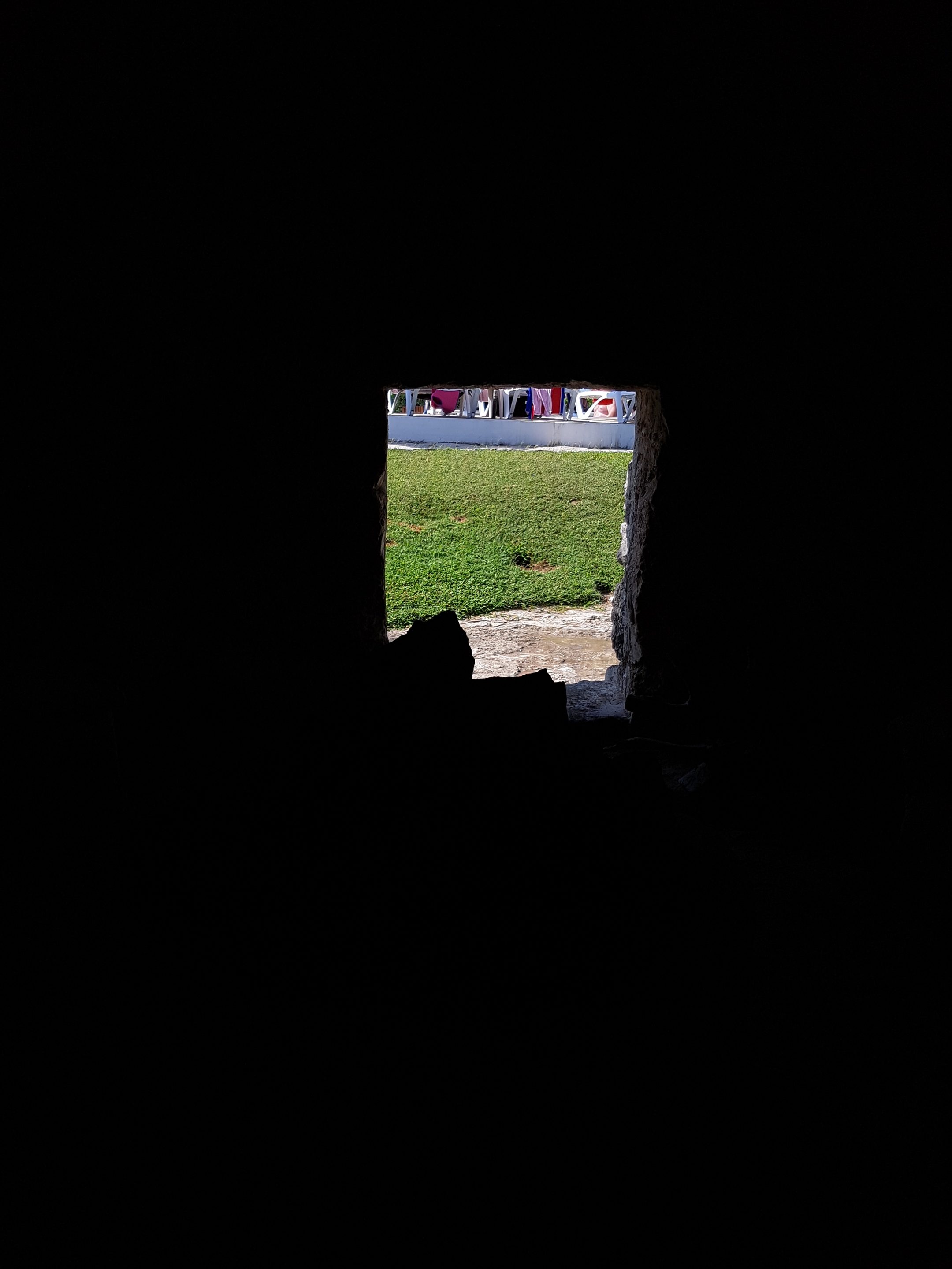 View from inside temazcal , darkness with a small opening showing daylight and grass outside